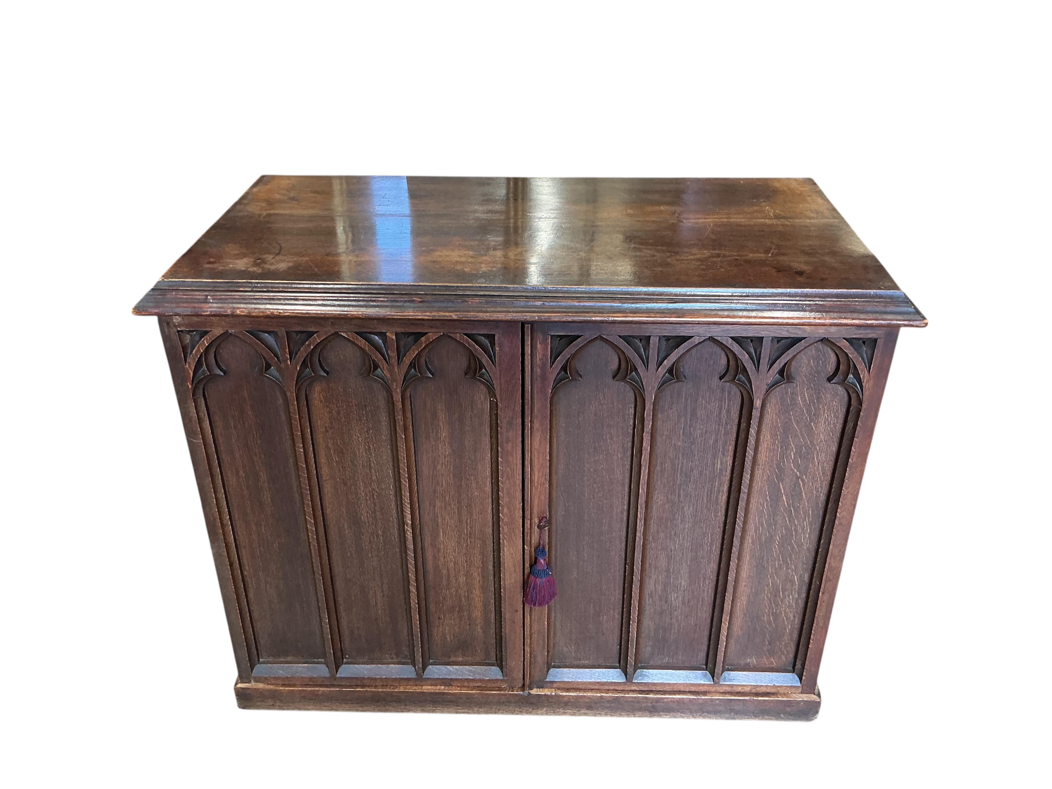 A late Victorian Gothic style oak two door side cabinet, width 122cm, depth 62cm, height 94cm